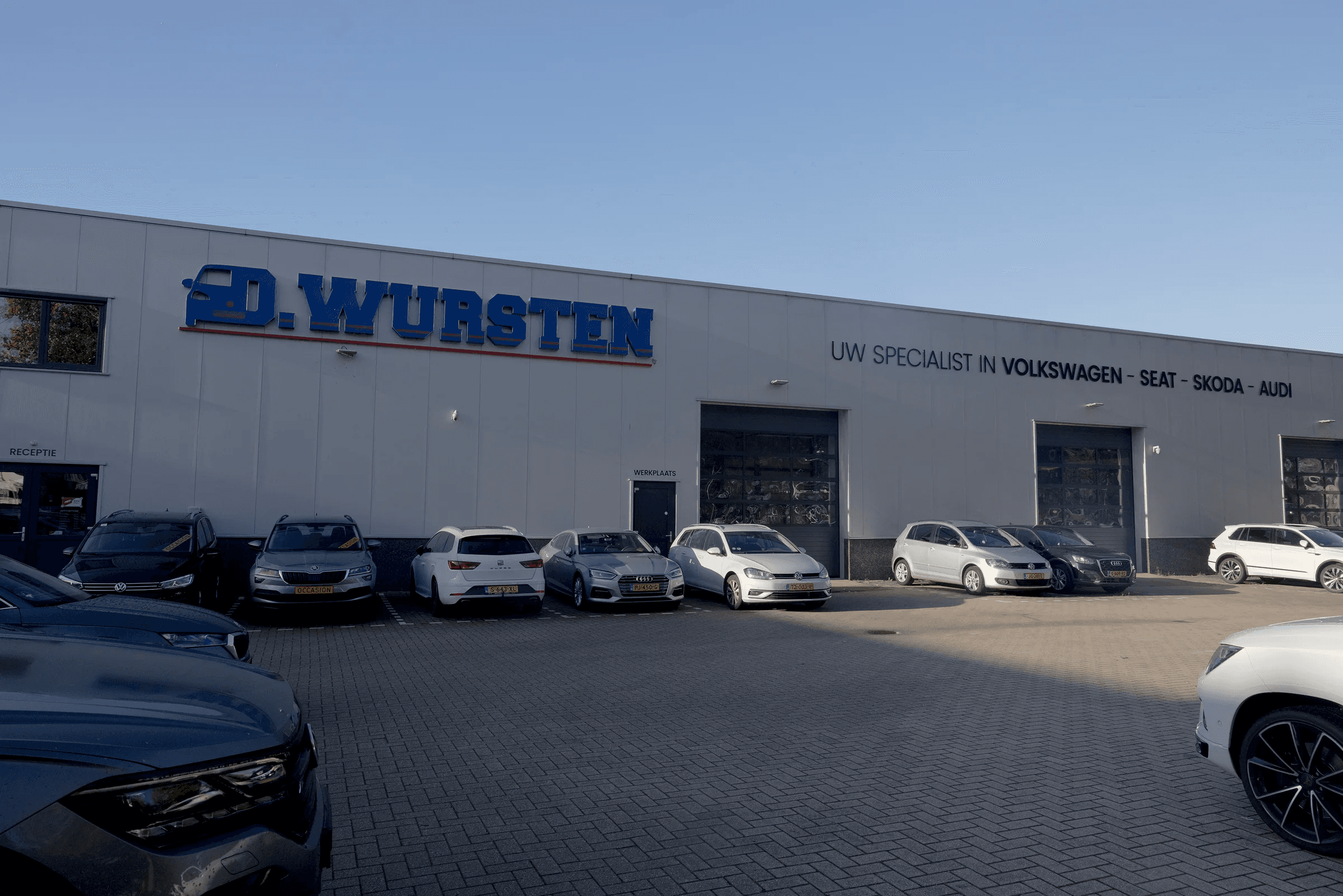 De gevel van Garage Wursten met de bedrijfsnaam en de werkplaats aan het voorterrein