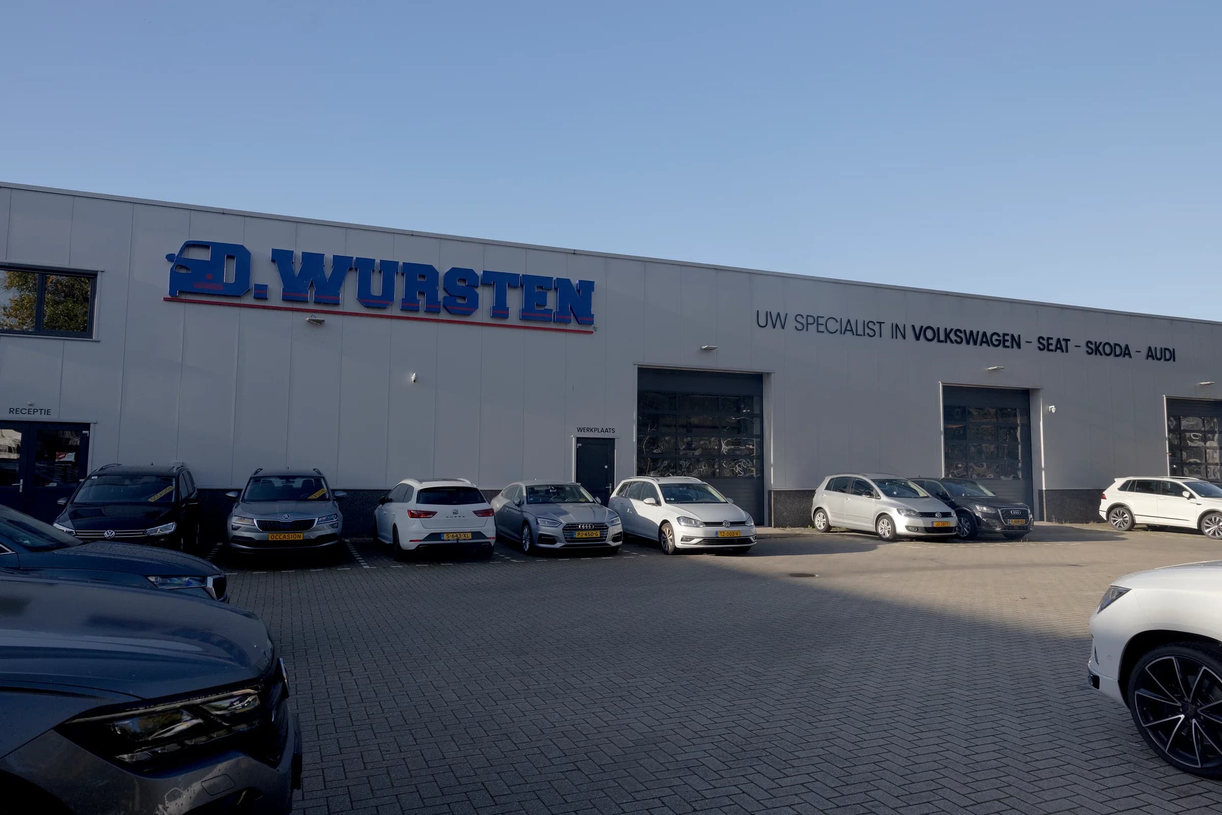 De gevel van Garage Wursten met de bedrijfsnaam en de werkplaats aan het voorterrein
