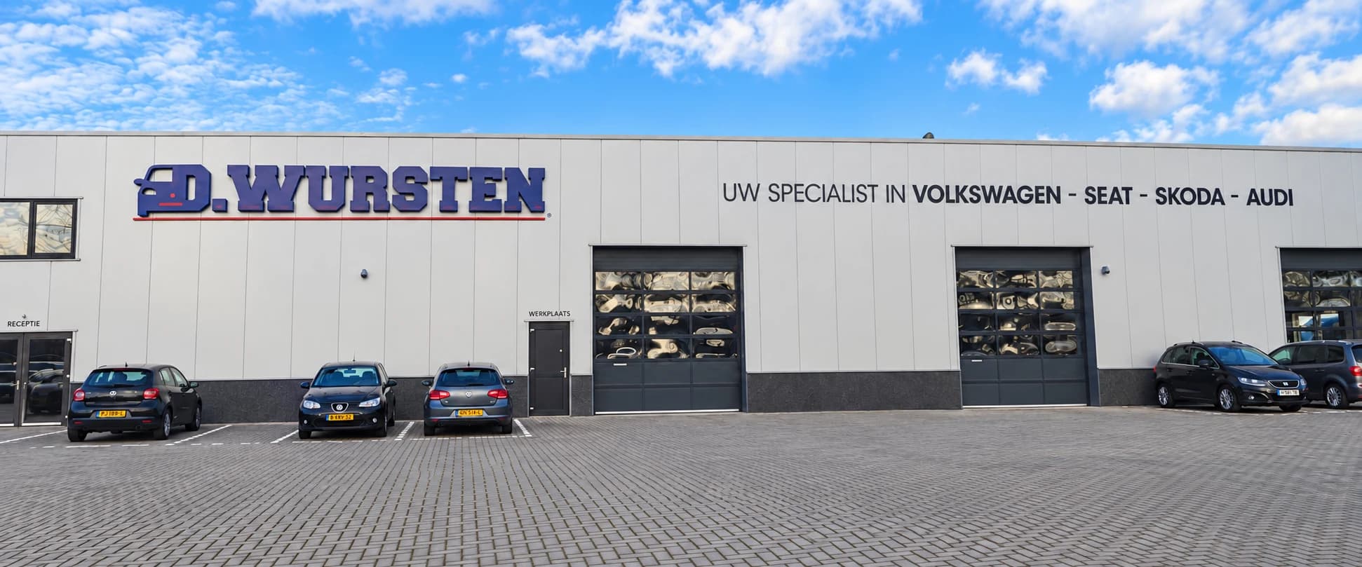 De gevel van Garage Wursten met de bedrijfsnaam en Volkswagen, Seat, Skoda en Audi op de gevel